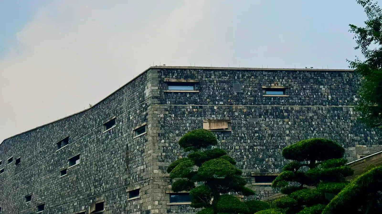 深色石墙建筑与修剪树木