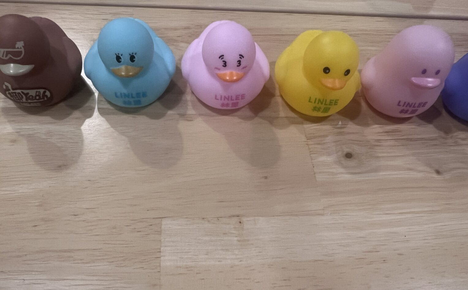 木质桌面上排列的彩色小鸭摆件